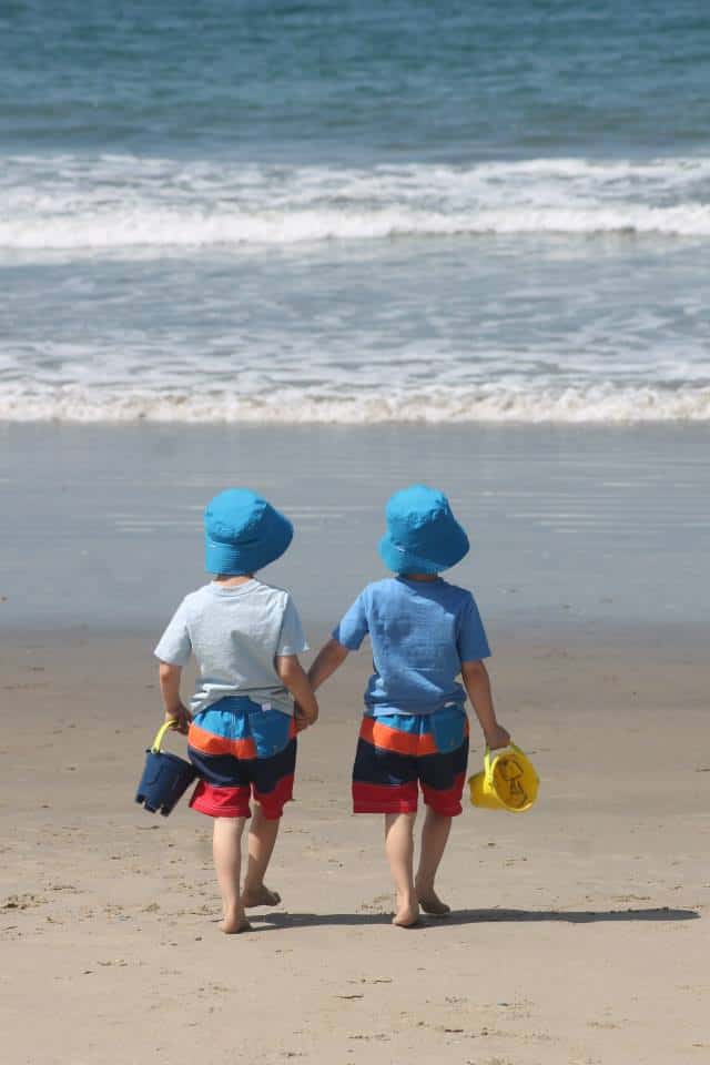 two kids at a beach with buckets