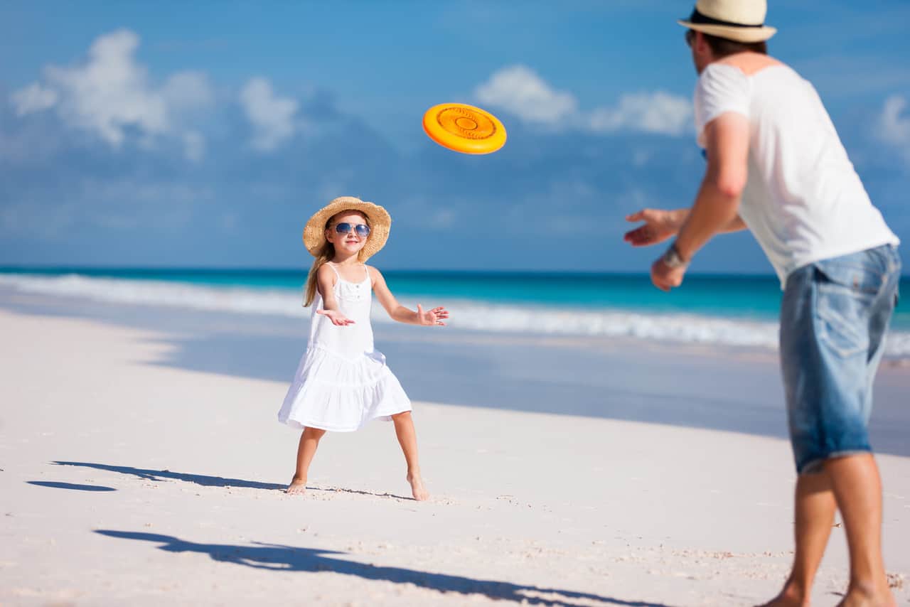 Father and daughter playing frisbee at beach
