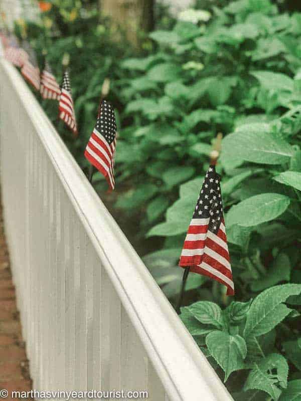 American flags on a white picket fence