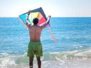 man flying a kite at the beach