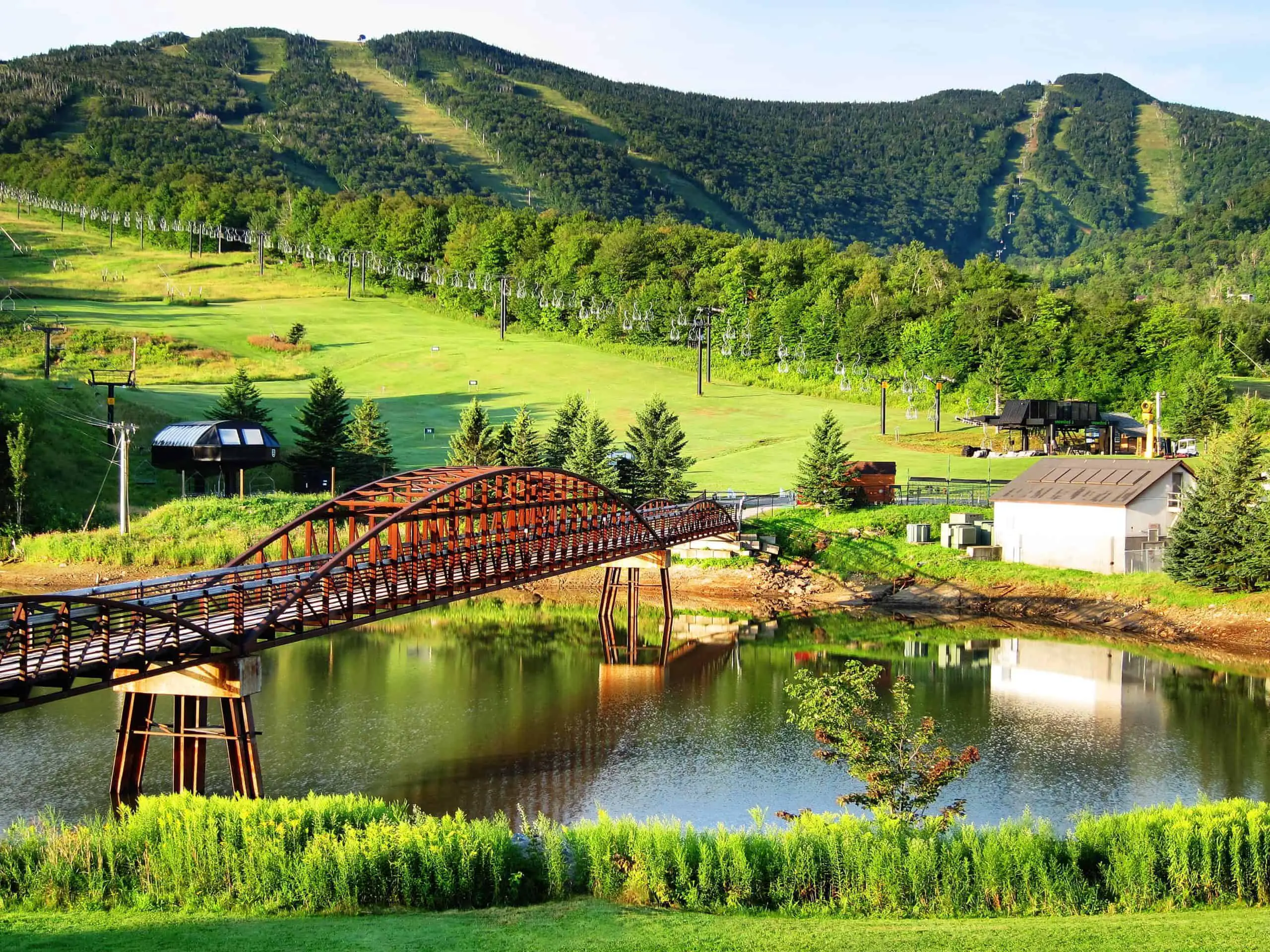 Vermont Green Mountains with a red metal bridge crossing the river and a white building