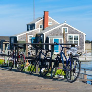 cycling nantucket in front of a grey shingle house
