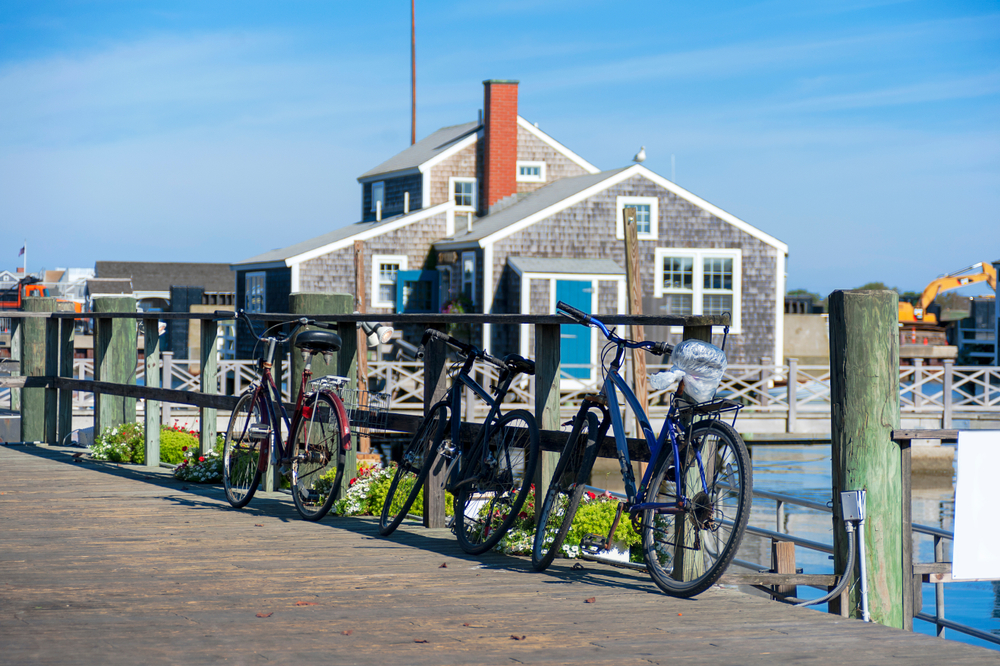 cycling nantucket in front of a grey shingle house